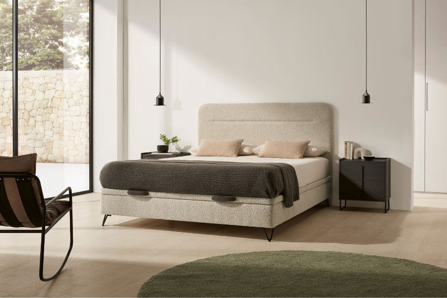 Canapé Vissuto Secret Contorno tapizado en beige con cabecero alto en dormitorio minimalista luminoso con ventanales