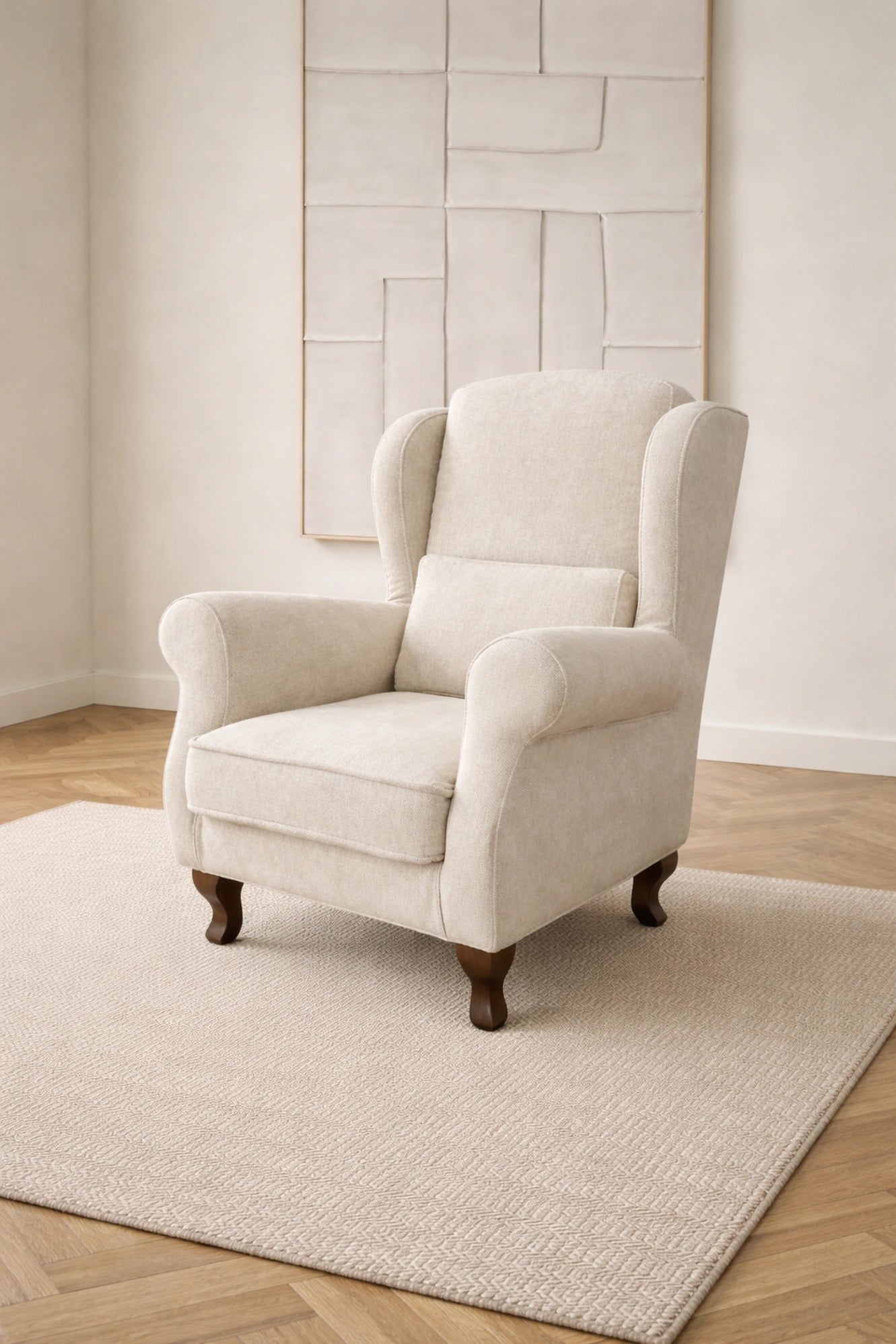 Butaca orejera Vissuto Bergamo tapizada en tela crema con patas de madera en salón clásico luminoso