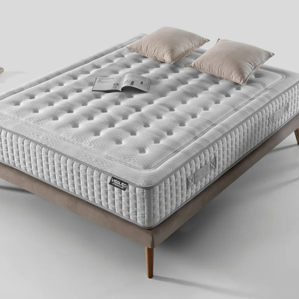 Imagen en dormitorio diáfano de colchón endurance de Vissuto sobre somier con patas de madera , cojines y libro