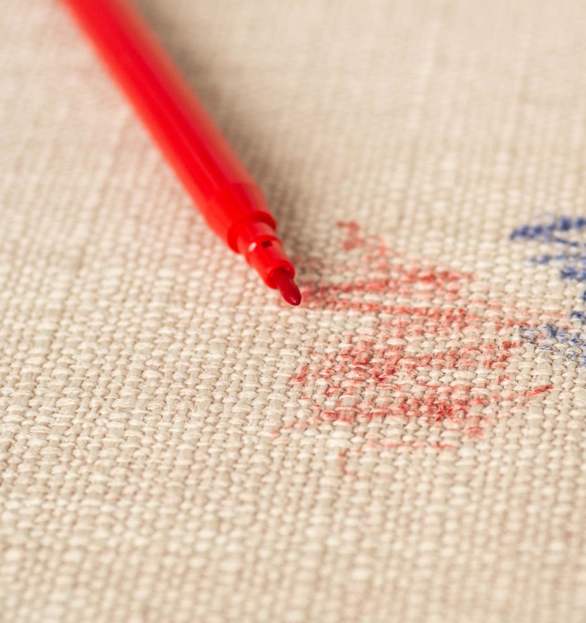 Tejido Vissuto de alta calidad: detalle de tela beige con hilo rojo y etiqueta bordada